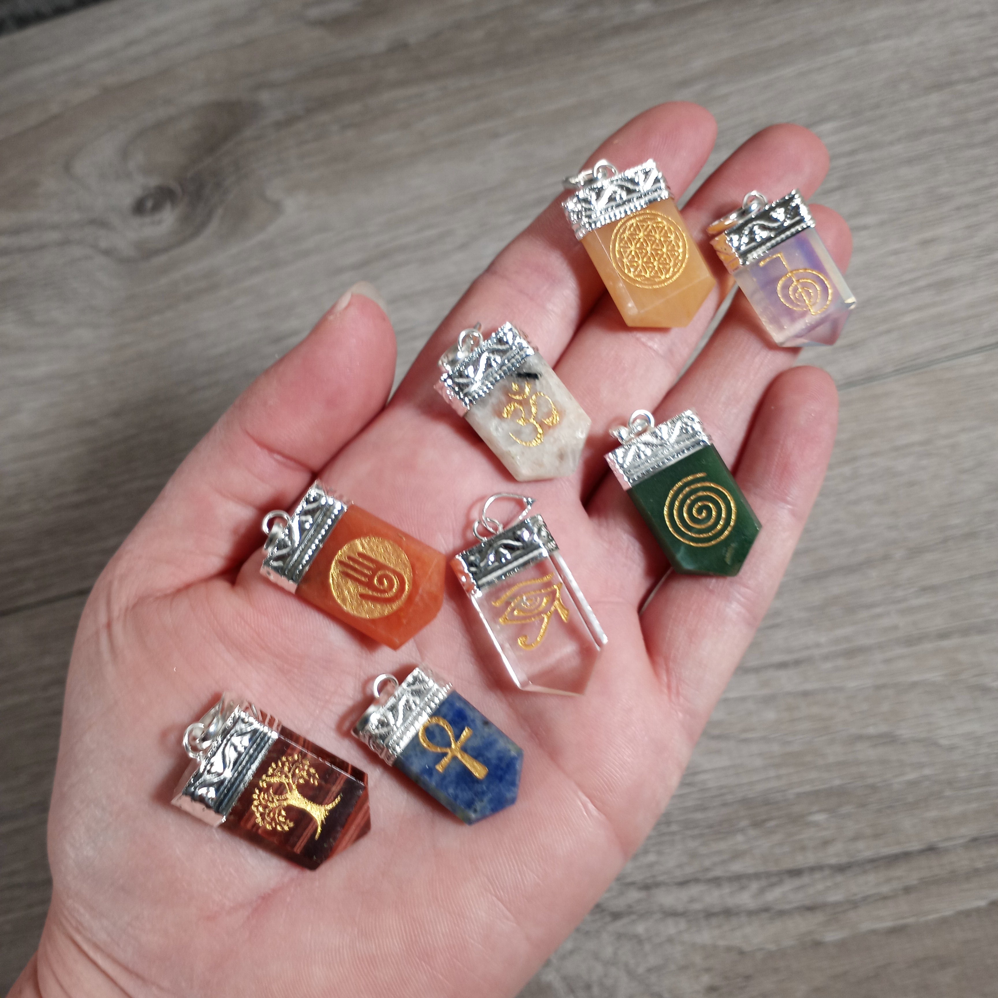 Assorted gemstone pendants with etched symbols in silver pot metal settings wholesale.