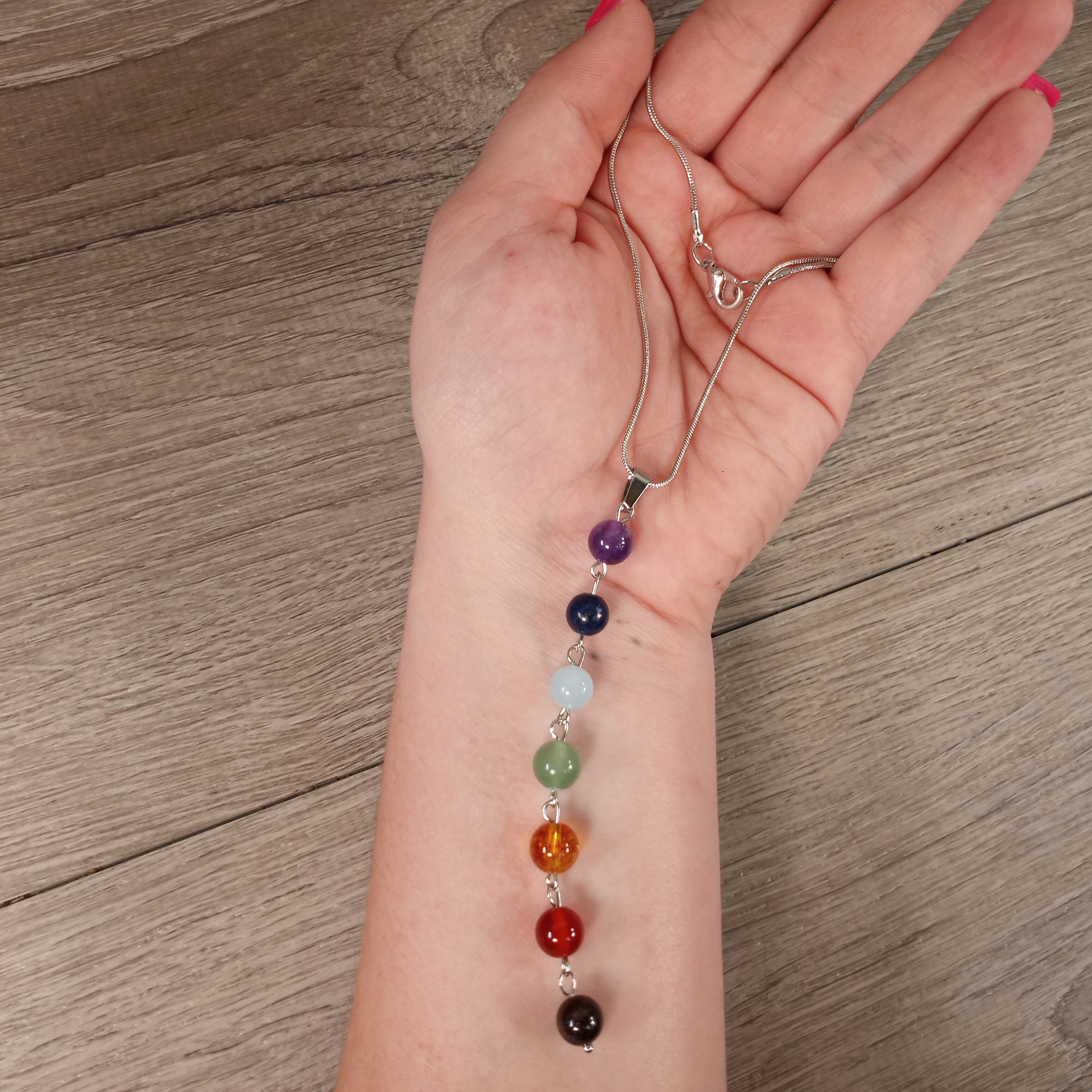 Chakra Drop Bead 8mm Necklace displayed on a jewelry stand for wholesale.