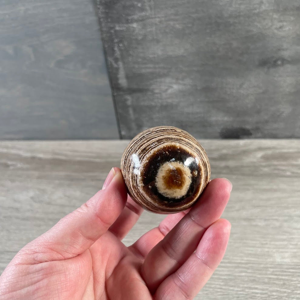 Polished Aragonite crystal sphere with earthy banding for wholesale crystal shops