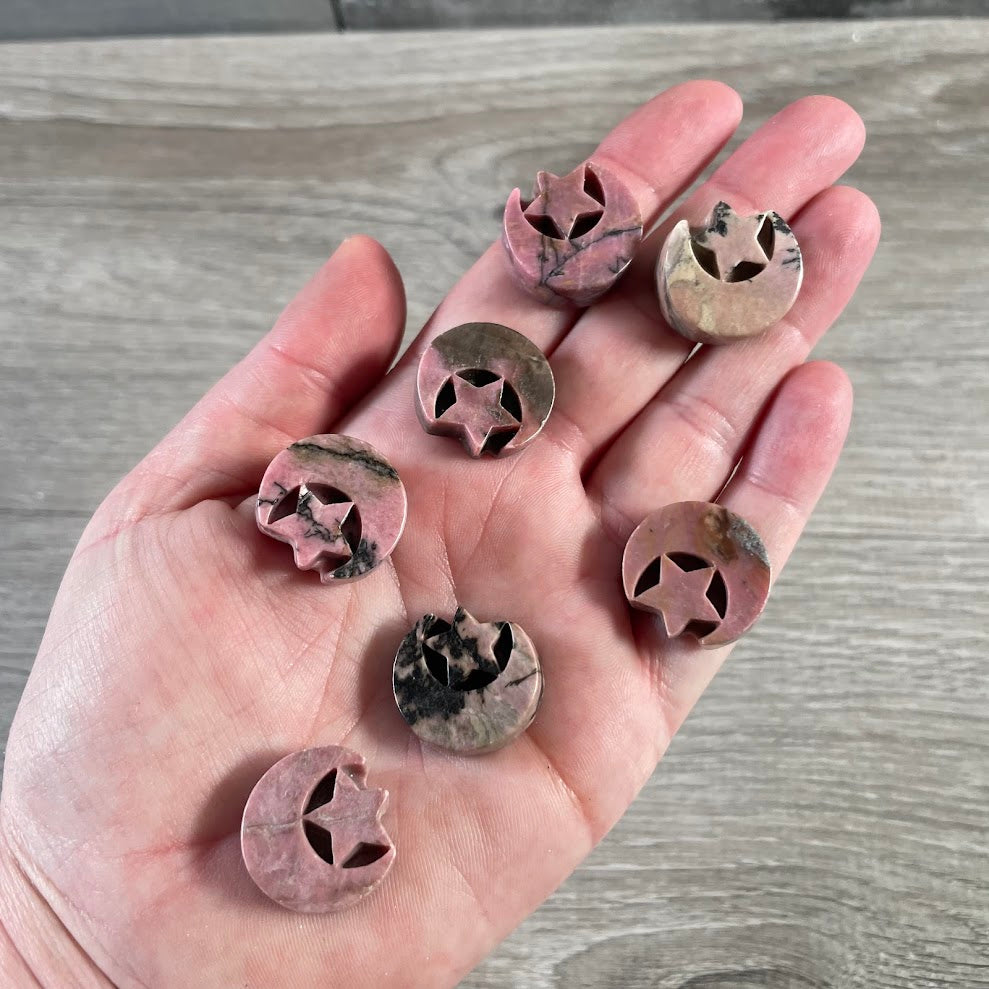 Rhodonite crescent moon carving with star shaped stone accent showing natural pink and black gemstone patterns.