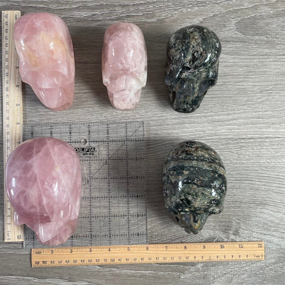 Lot of 5 crystal skulls; three rose quartz and two Kabamba jasper for display
