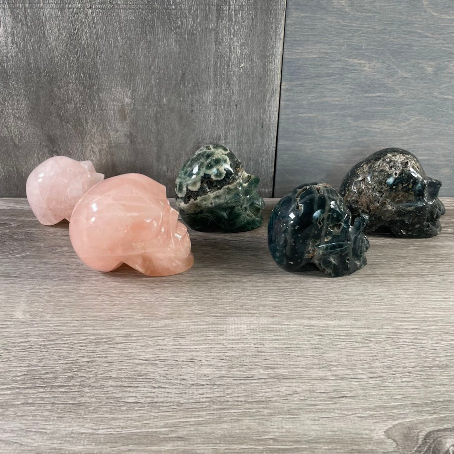 Lot of two rose quartz and three Kambaba jasper skulls; facing-sideways.