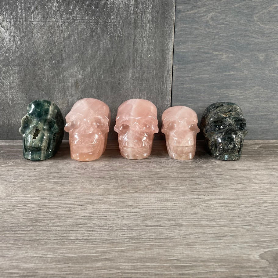 Lot of three rose quartz and two Kambaba jasper skulls; facing forward.