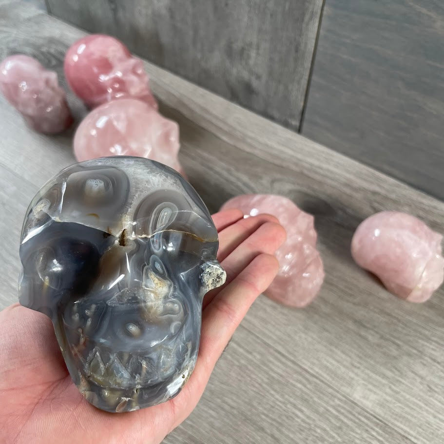 Close up of Botswana agate skull with rose quartz skulls in the background.