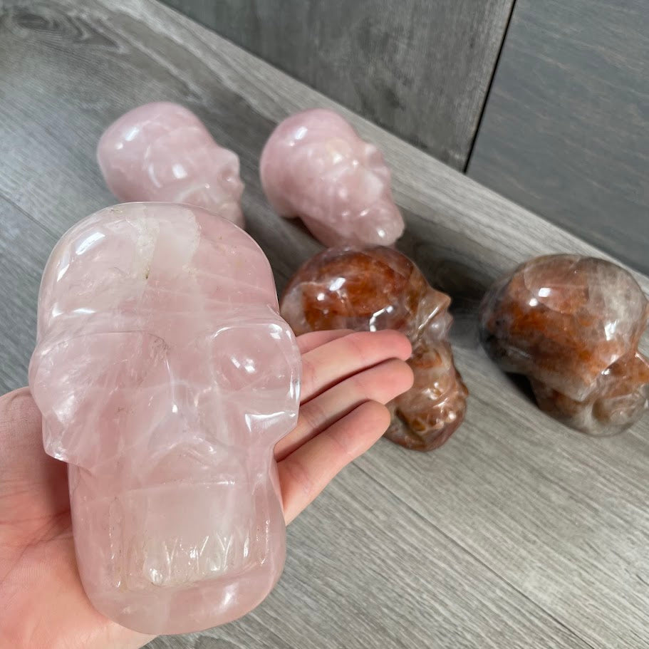 Close up of rose quartz skull with other skulls in the background.