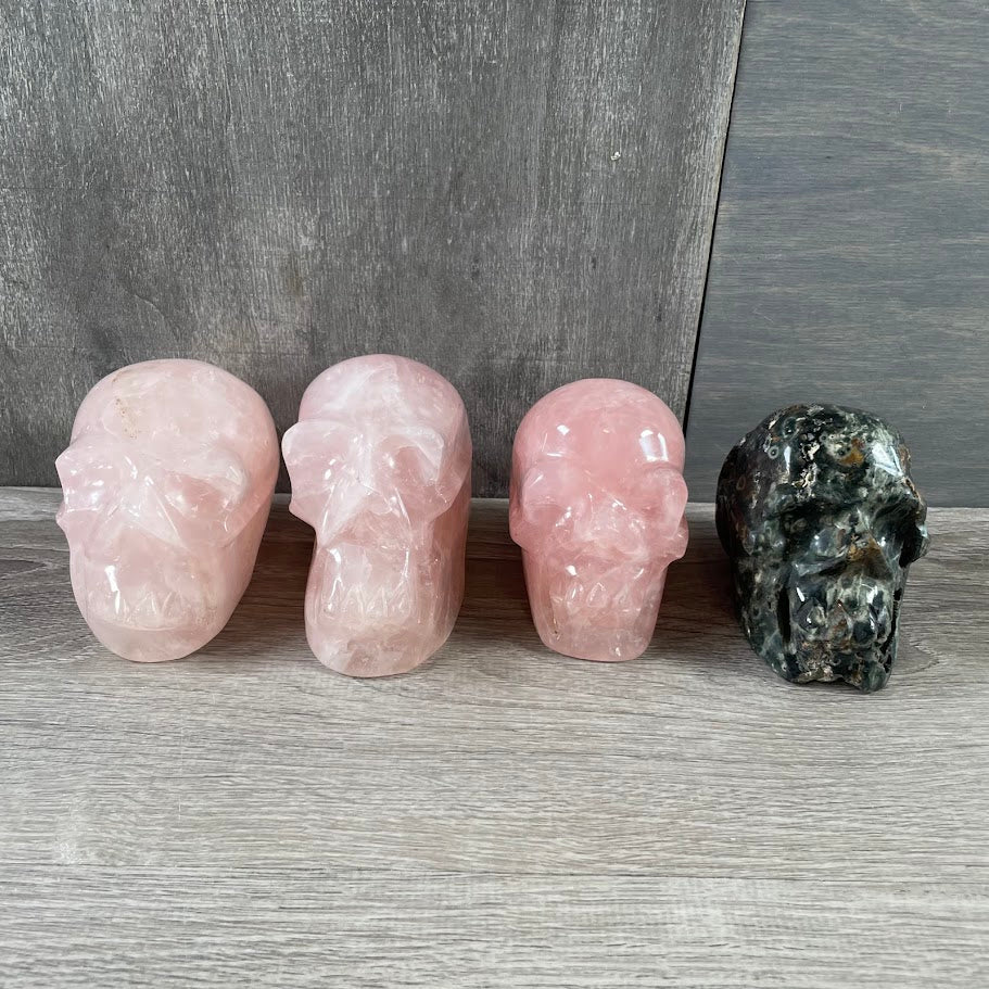 Lot of three rose quartz skulls and one Kambaba jasper skull; facing forwards.