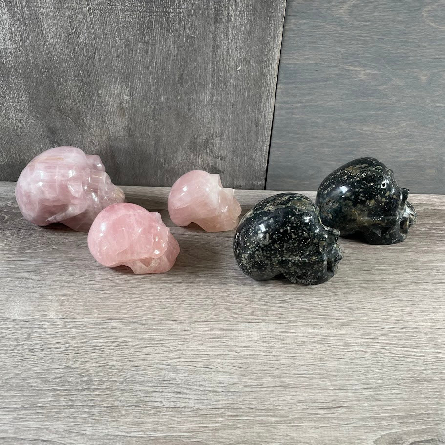 Lot of three rose quartz skulls and two Kambaba jasper skulls; facing sideways.