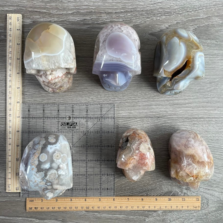 Lot of six crystal skulls: three quartz and three agate. With grid and rulers for size reference.
