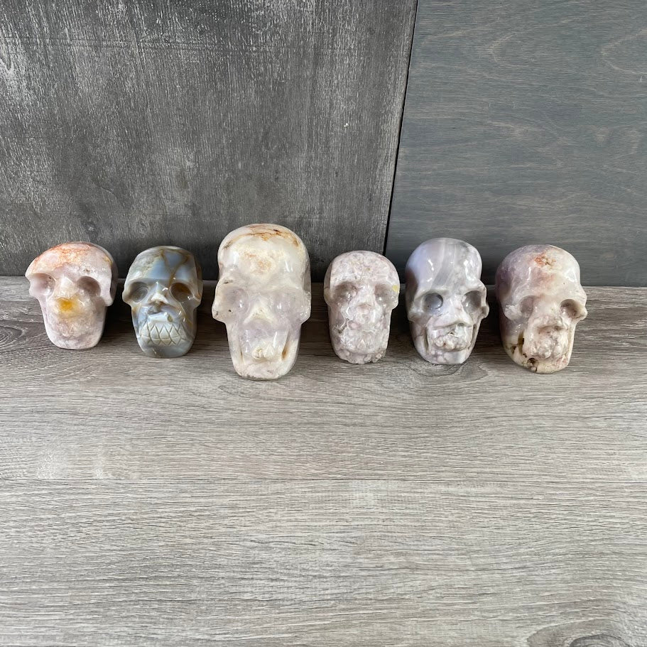 Lot of four quartz and two agate skulls; facing forwards.