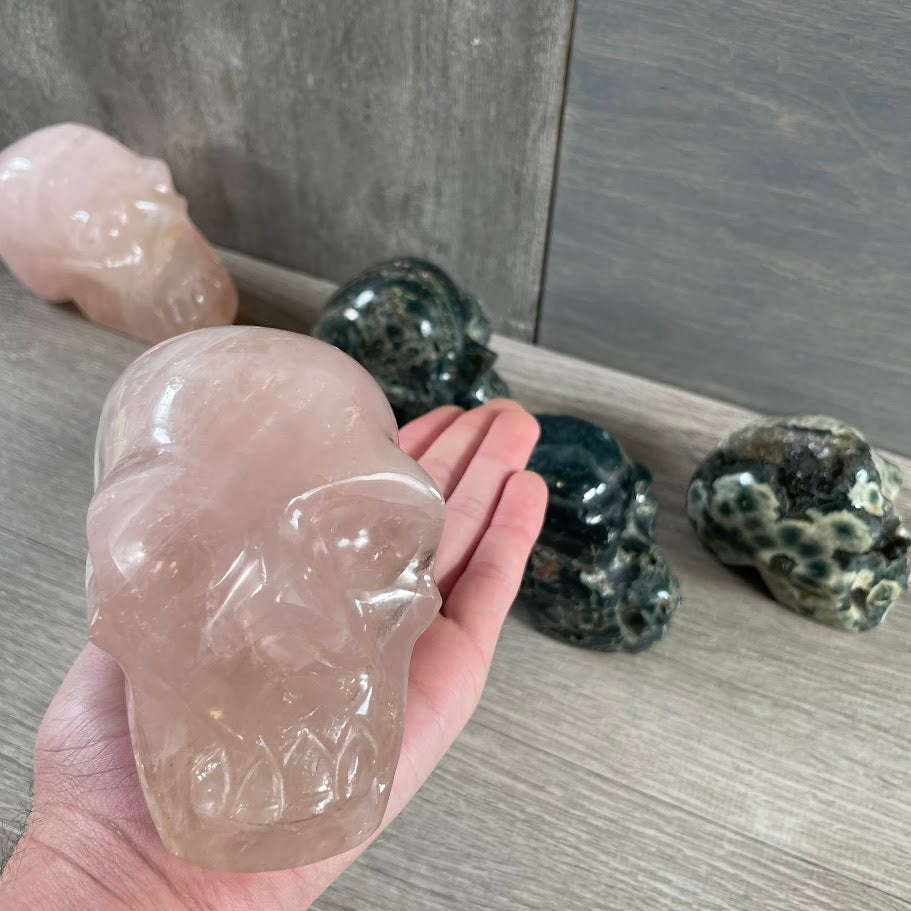 Close up of rose quartz skull with other skulls in the background.