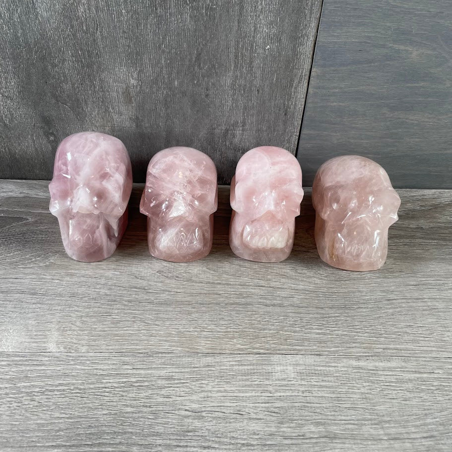 Lot of four rose quartz skulls; facing forwards.