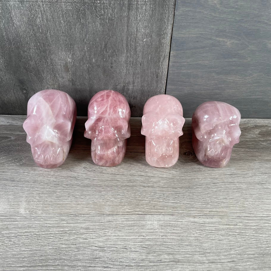 Lot of four rose quartz skulls; facing forwards.