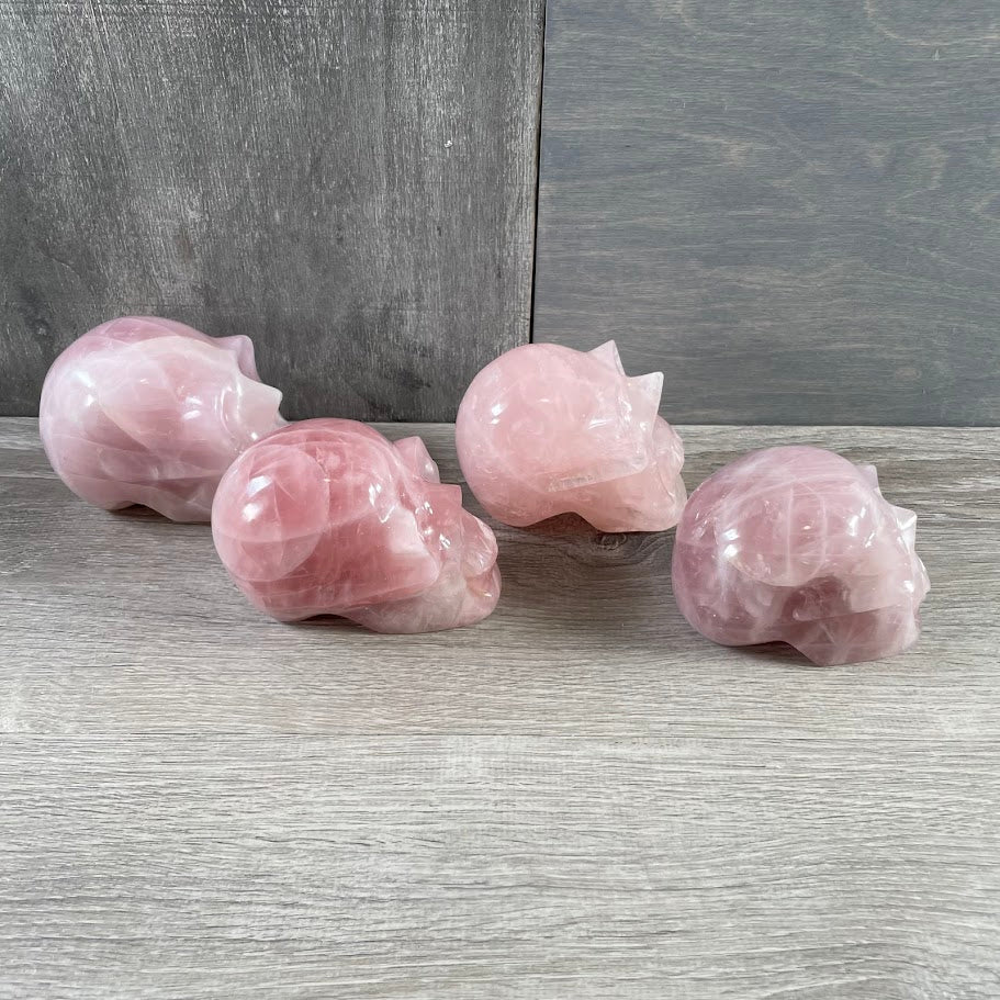 Lot of four rose quartz skulls; facing sideways.