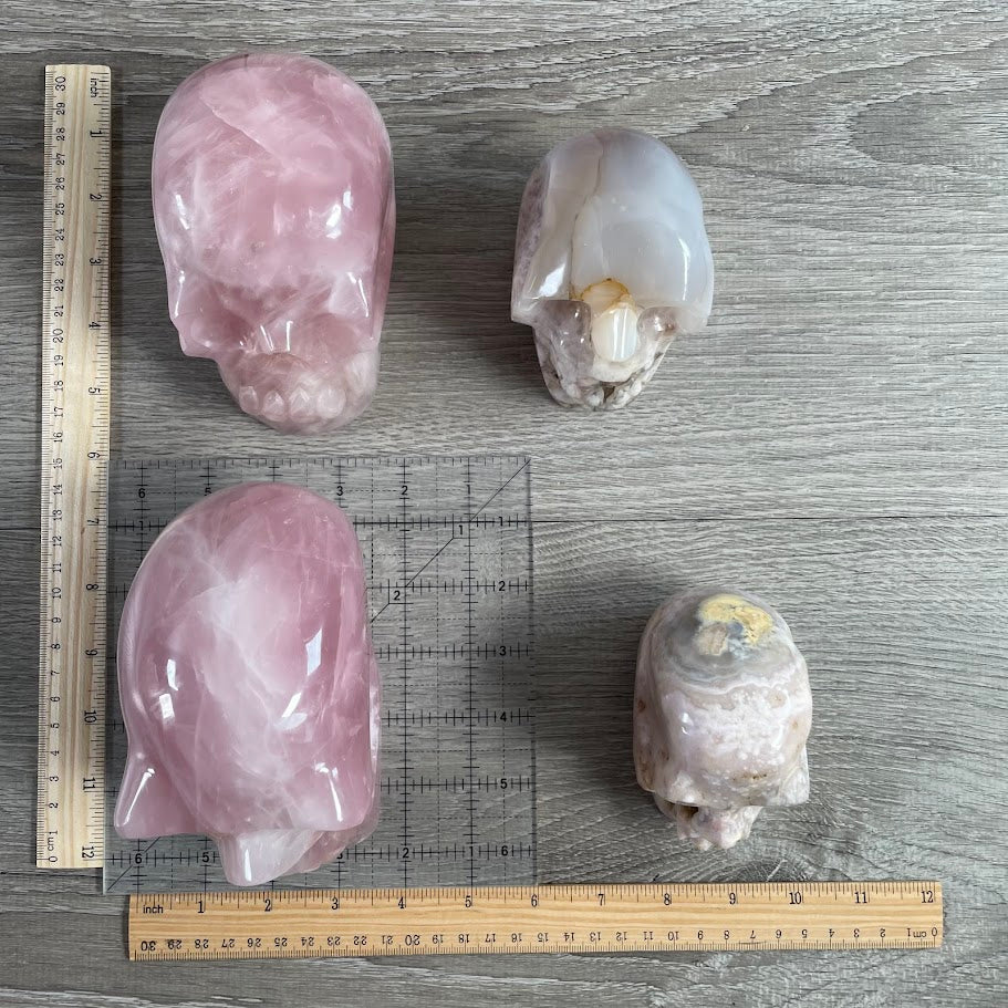 Lot of two rose quartz and two quartz skulls with grid and rulers for size reference.