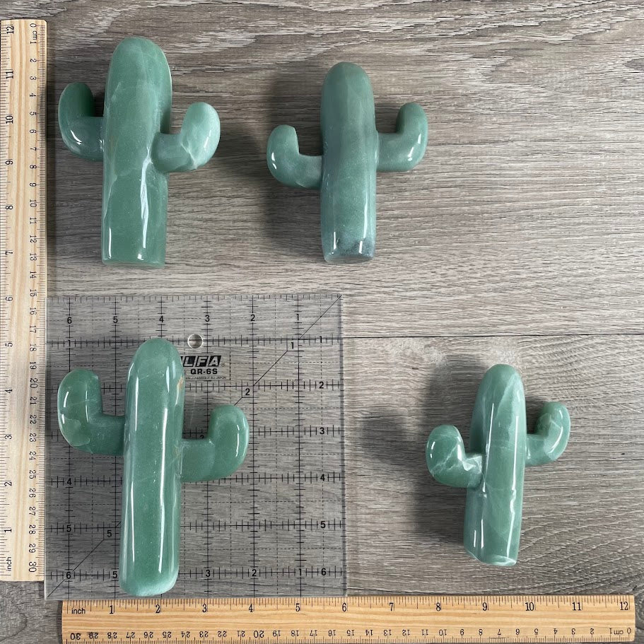 Four aventurine cacti figurines with grid and rulers for size reference.