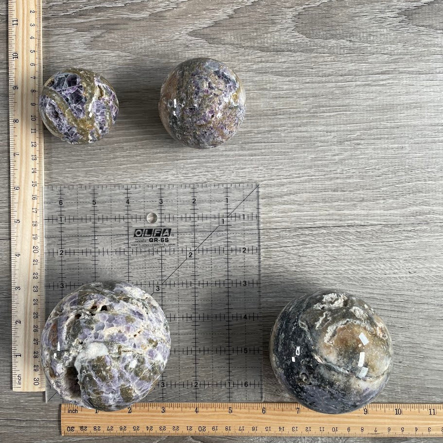 Lot of four fluorite vug spheres with grid and rulers for size reference.