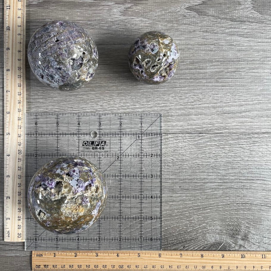 Lot of three fluorite vug spheres with grid and rulers for size reference.