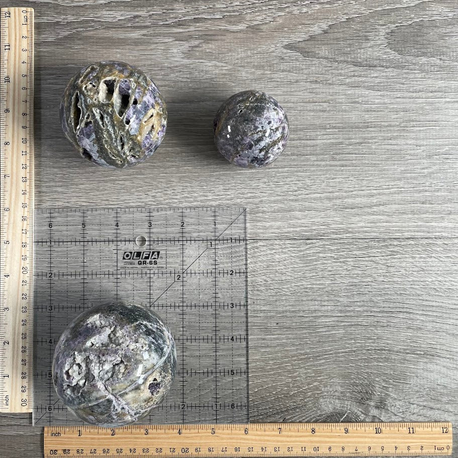 Lot of three fluorite vug spheres with grid and rulers for size reference.