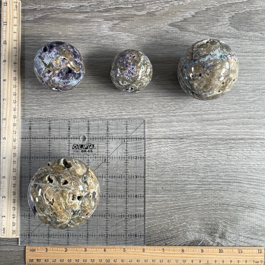 Lot of four fluorite vug spheres with grid and rulers for size reference.