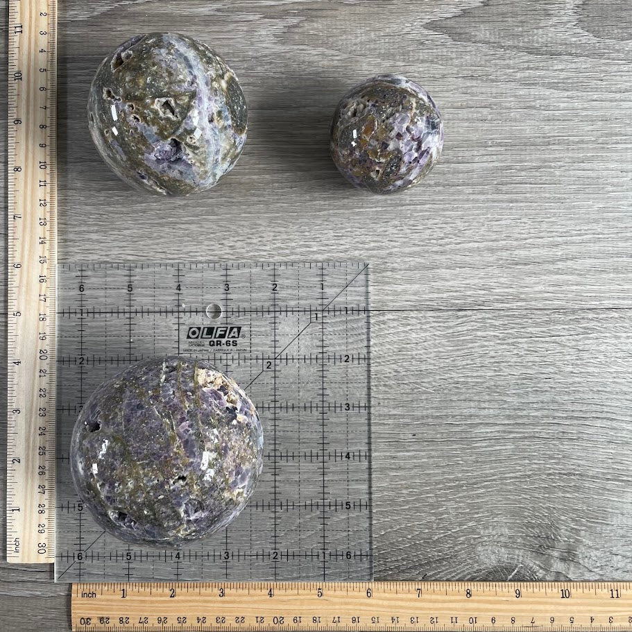 Lot of three fluorite vug spheres with grid and rulers for size reference.