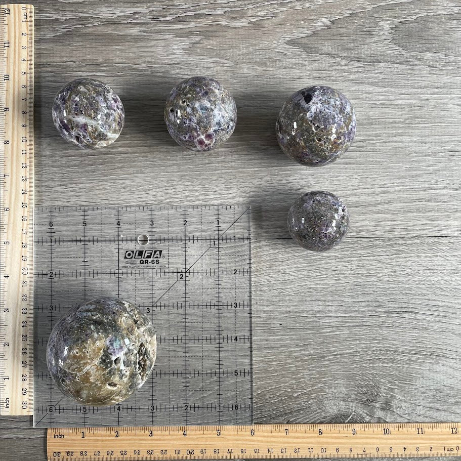 Lot of five fluorite vug spheres with grid and rulers for size reference.