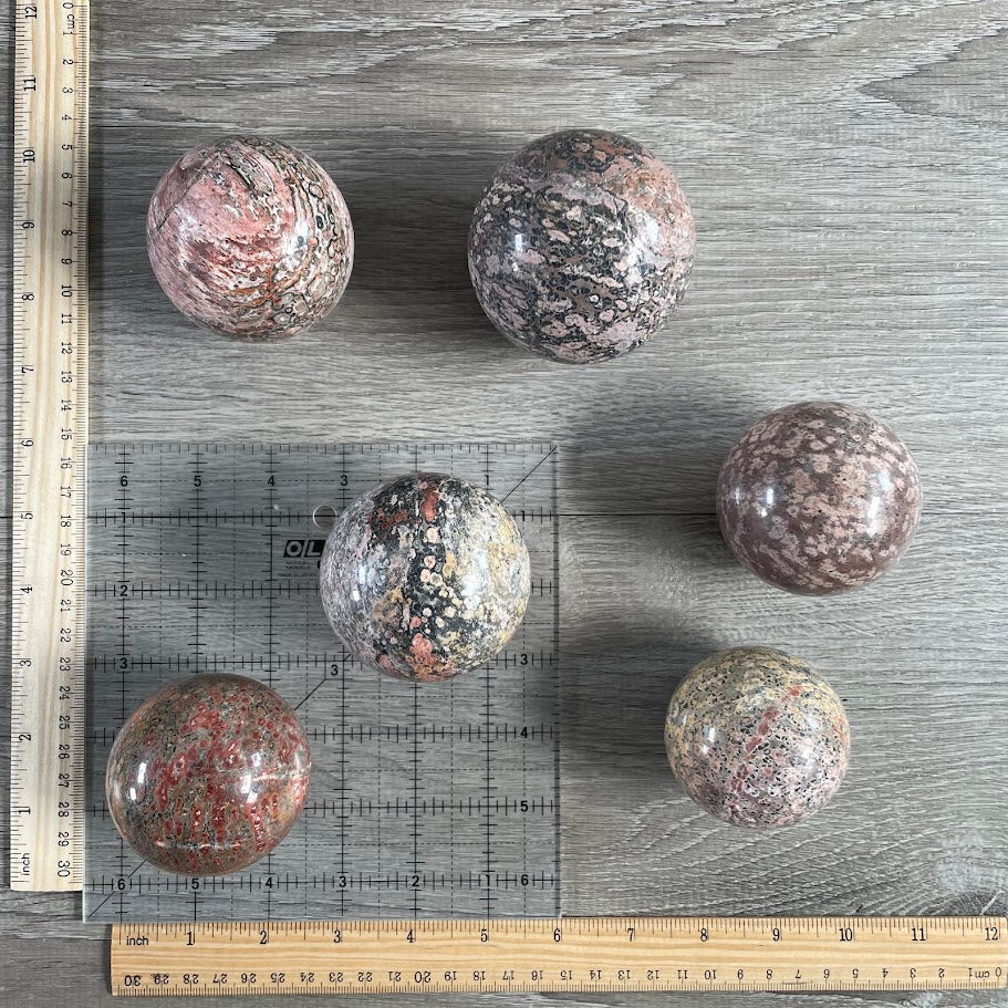 Lot of six leopard skin jasper spheres with grid and rulers for size reference.