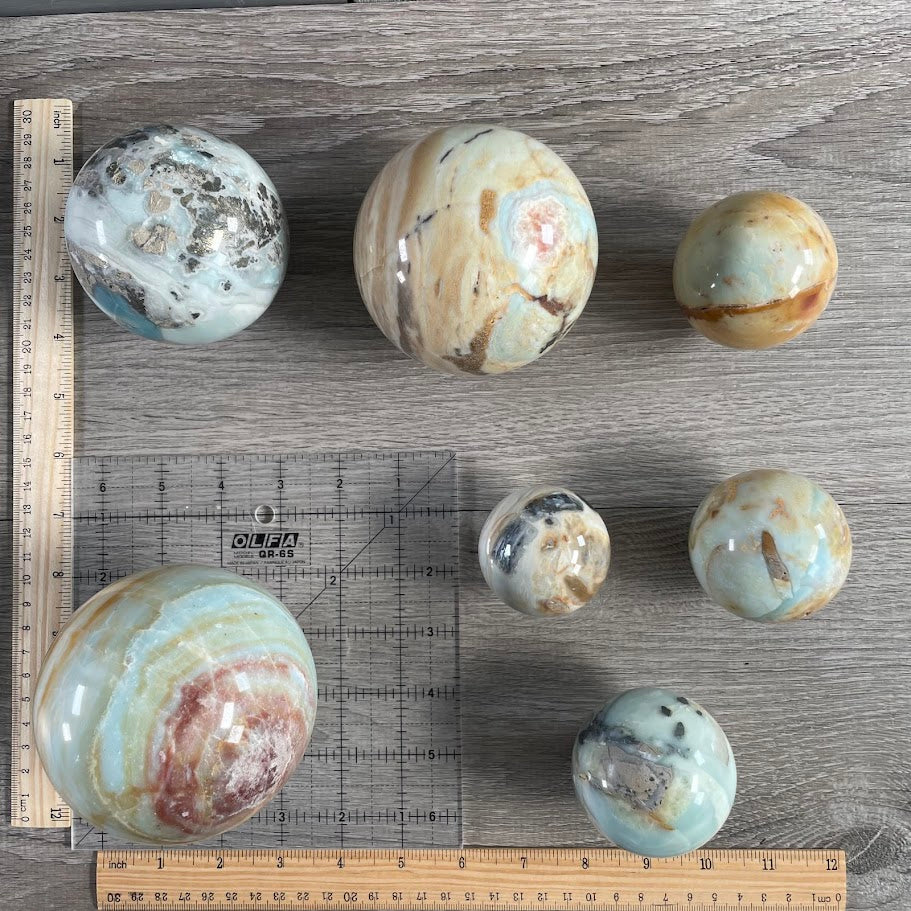 Lot of seven amazonite spheres with grid and rulers for size reference.