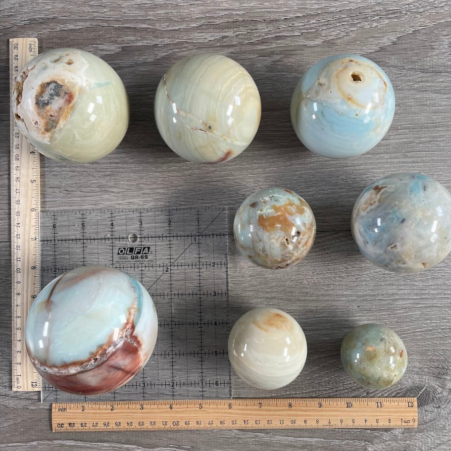 Lot of eight amazonite spheres with grid and rulers for size reference.