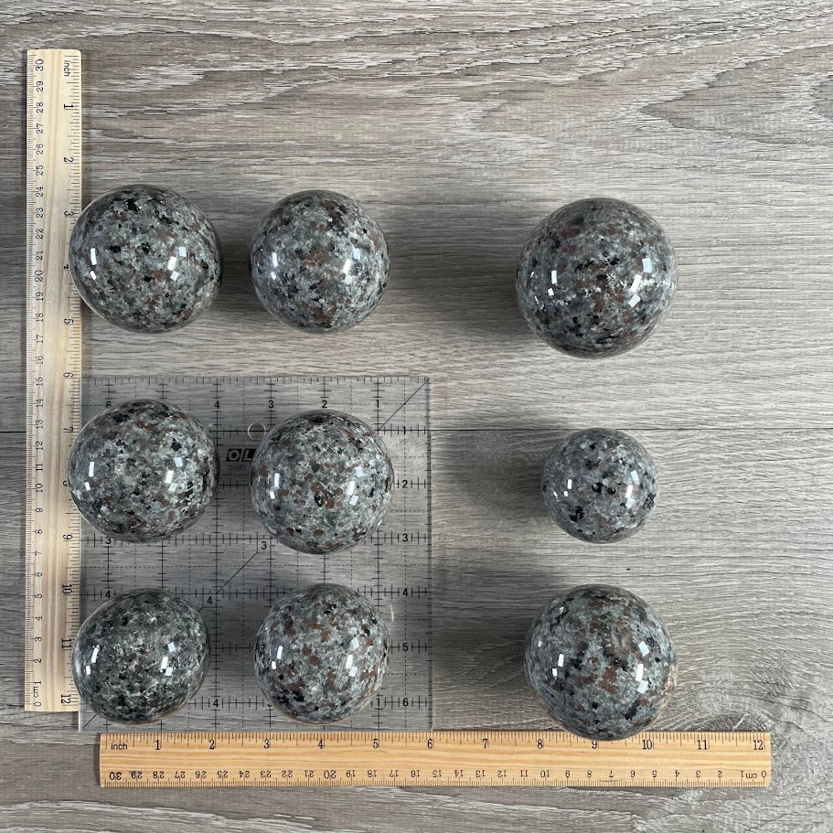 Lot of nine flame stone spheres with grid and rulers for size reference.