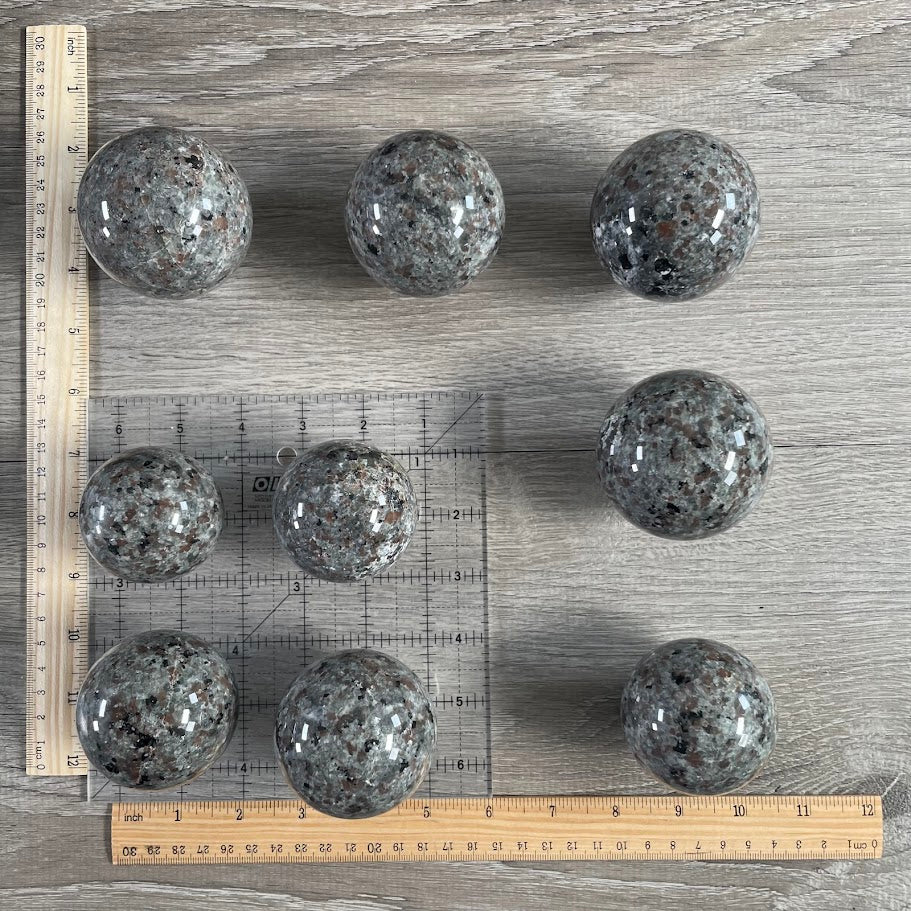 Lot of nine flame stone spheres with grid and rulers for size reference.