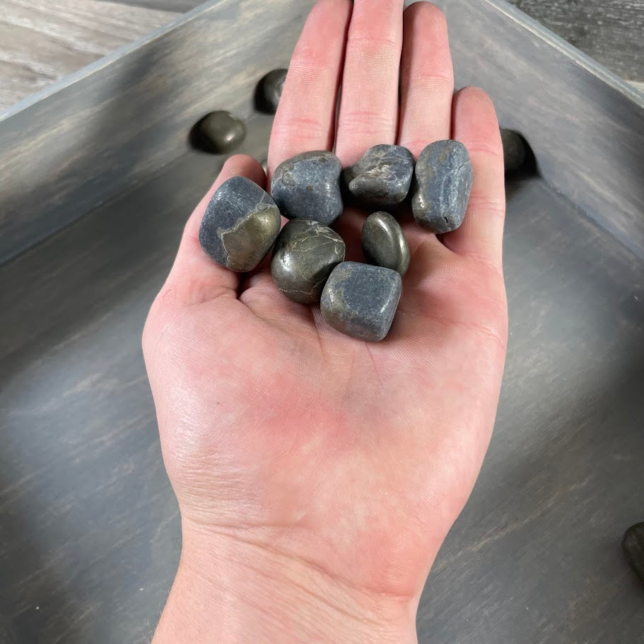 Hand holding Pyrite tumbled stones for scale – 1 lb wholesale lot