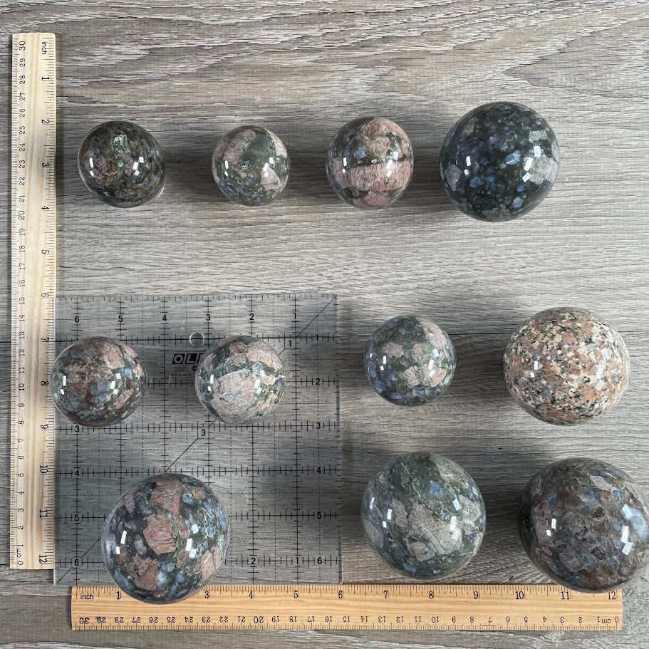 Lot of eleven que sera spheres with grid and rulers for size reference.