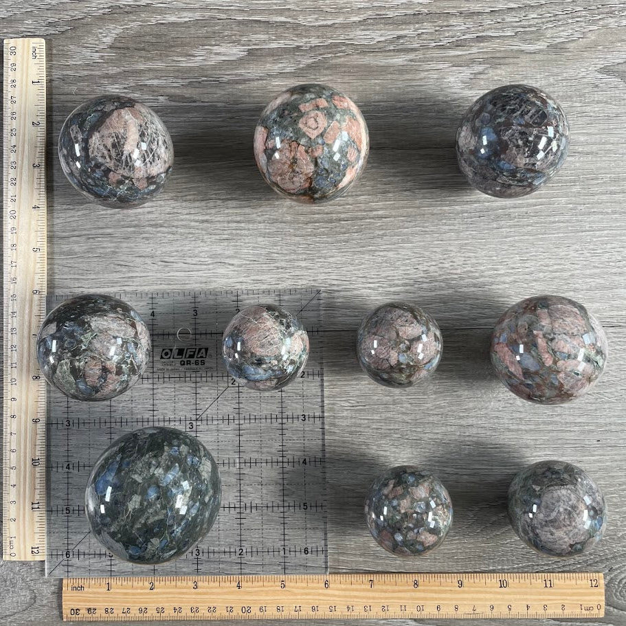 Lot of ten que sera spheres with grid and rulers for size reference.