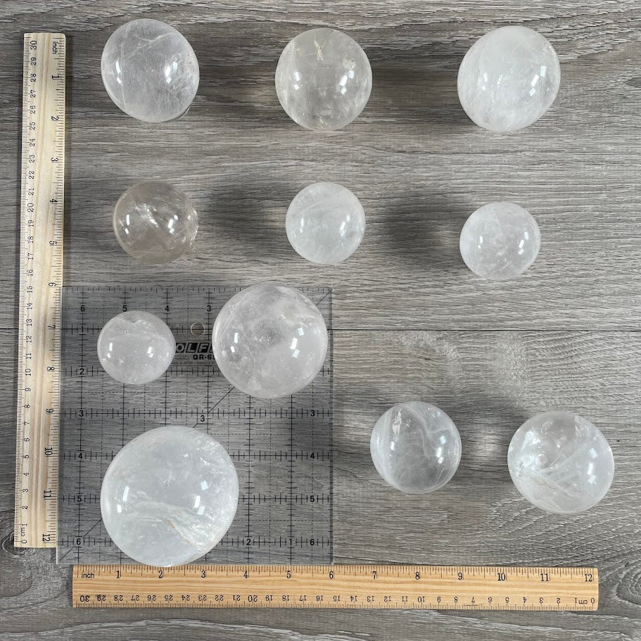 Lot of eleven quartz spheres with grid and rulers for size reference.