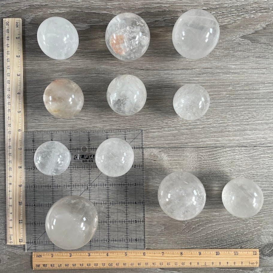Lot of eleven quartz spheres with grid and rulers for size reference.