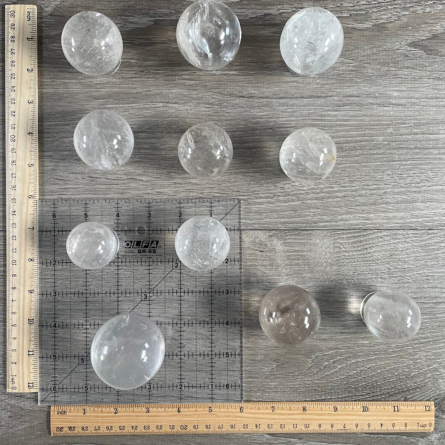 Lot of eleven quartz spheres with grid and rulers for size reference.