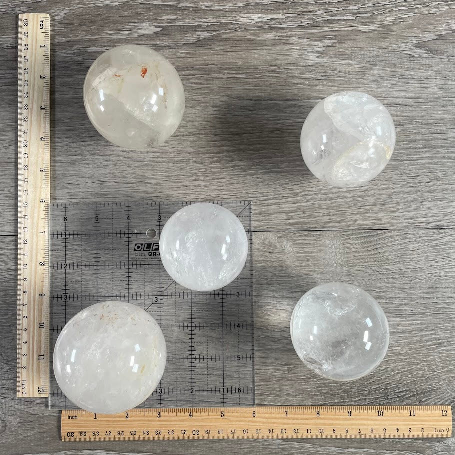 Lot of five quartz spheres with grid and rulers for size reference.