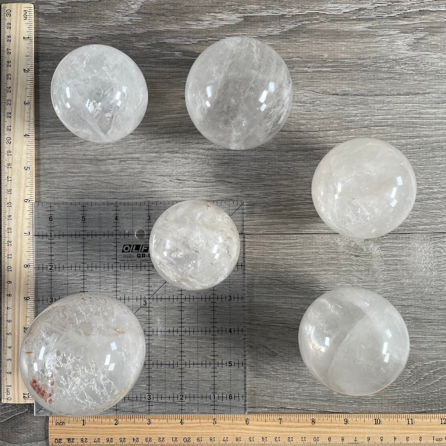 Lot of six quartz spheres with grid and rulers for size reference.