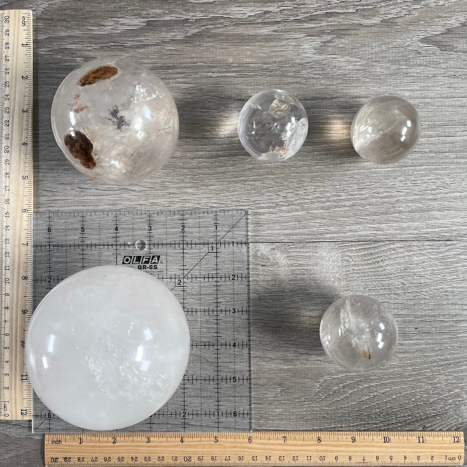 Lot of five quartz spheres with grid and rulers for size reference.