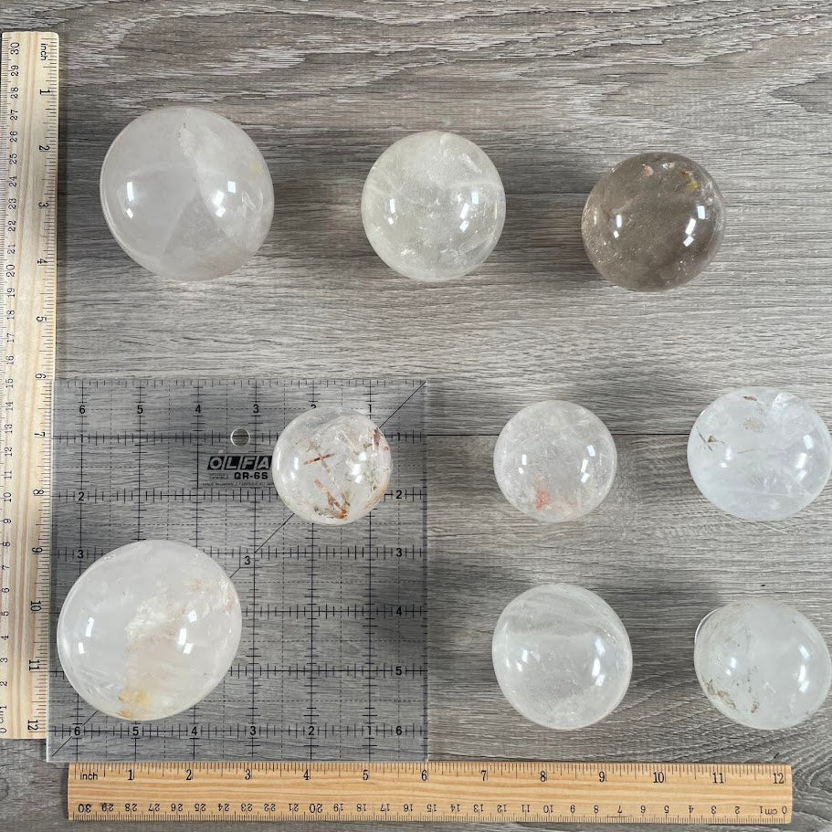 Lot of nine quartz spheres with grid and rulers for size reference.