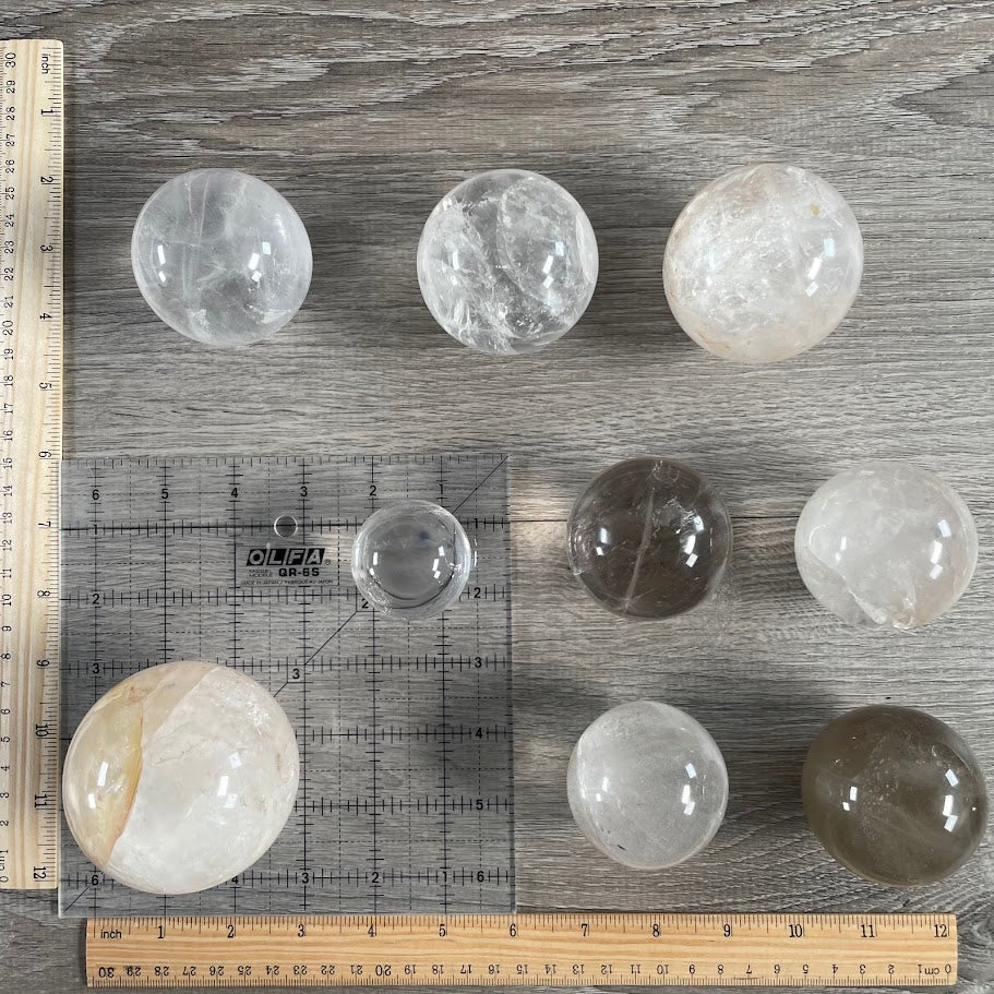 Lot of 9 quartz spheres with grid and rulers for size reference.