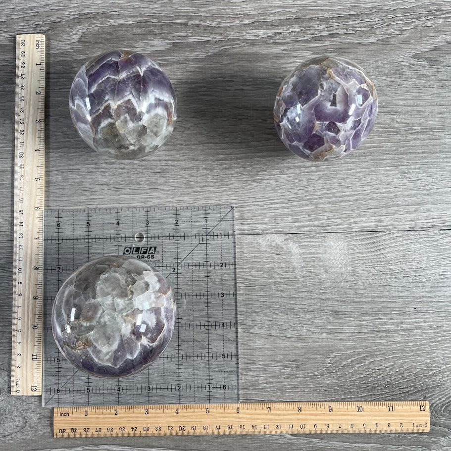 Lot of three amethyst spheres with grid and rulers for size reference.