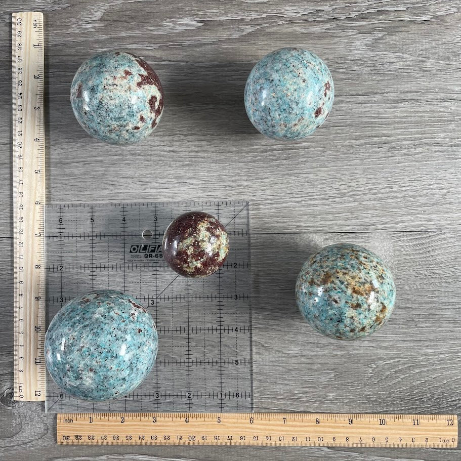 Lot of five amazonite with biotite spheres with grid and rulers for size reference.