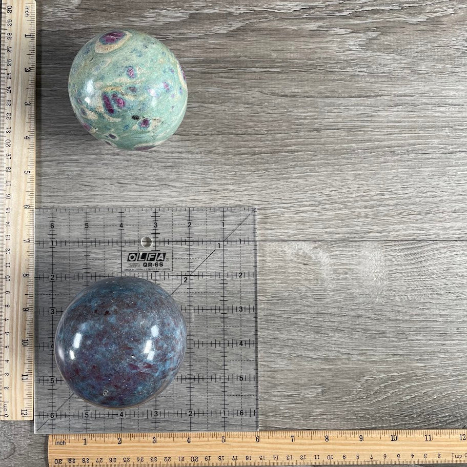 Lot of two; one ruby in zoisite sphere, one ruby in kyanite sphere with grid and rulers for size reference.
