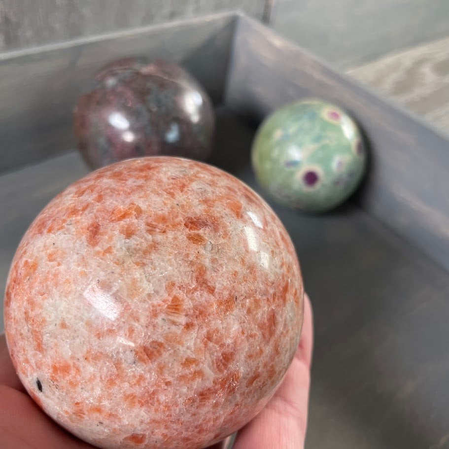 Close up of sunstone sphere with other spheres in the background for new age stores.