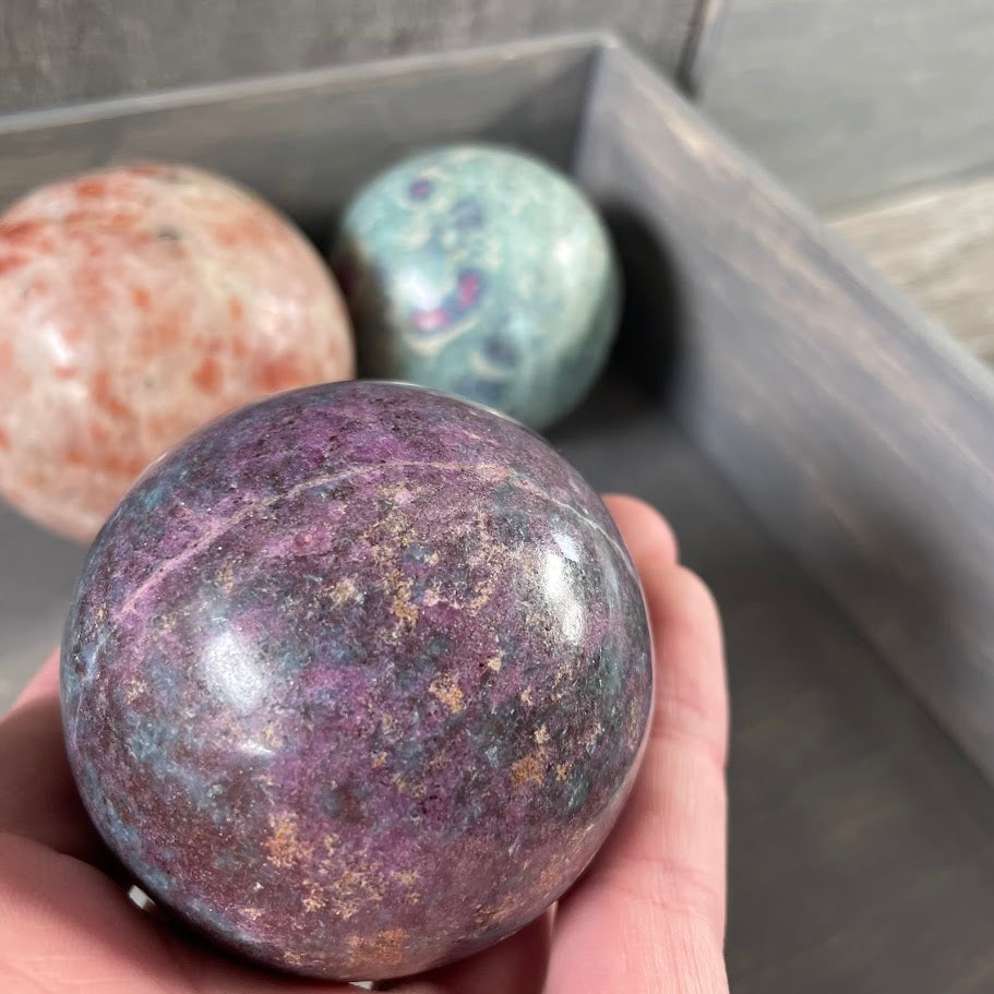 Close up of ruby in kyanite sphere with sunstone and ruby in zoisite spheres in the background.