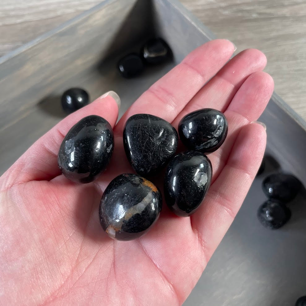 Black tourmaline stones polished into smooth tumbled pieces for resale and collecting