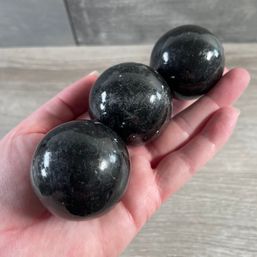 Polished nuummite crystal sphere for wholesale gemstone displays