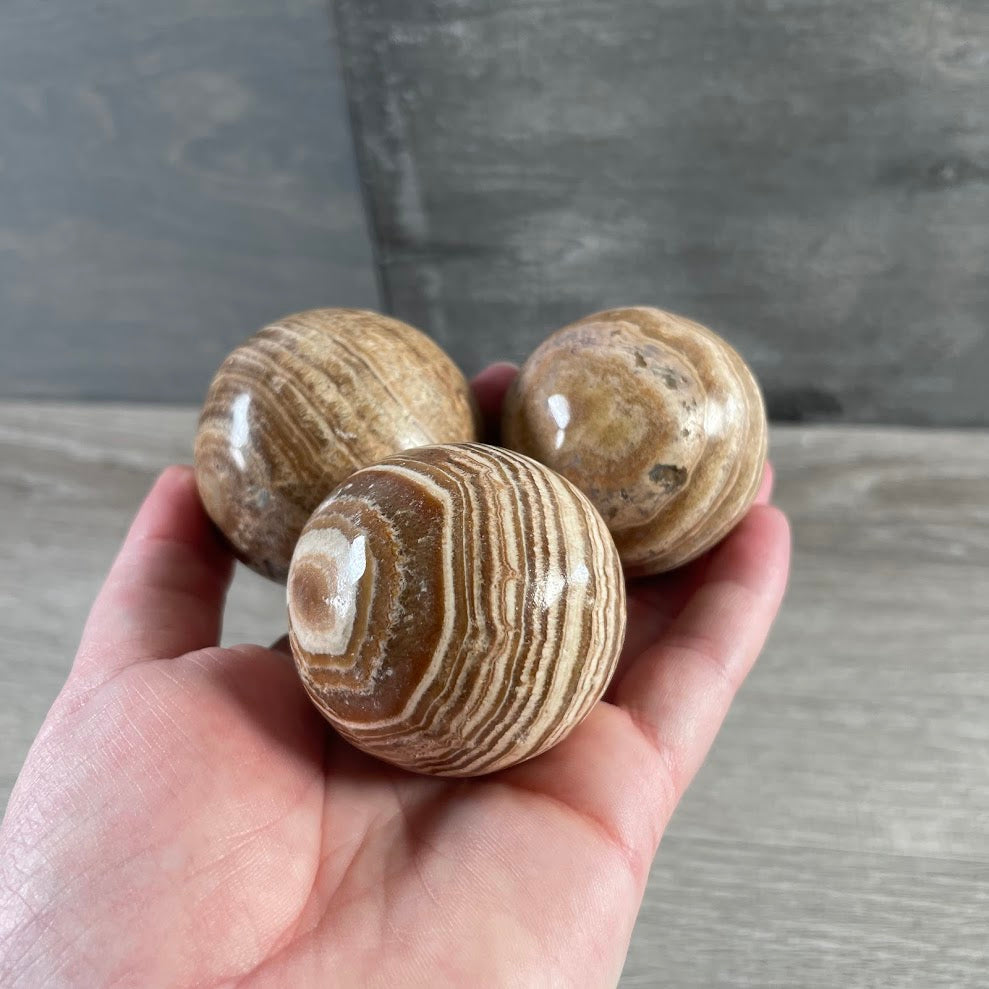 Earth tone Aragonite sphere with layered mineral patterns and polished finish