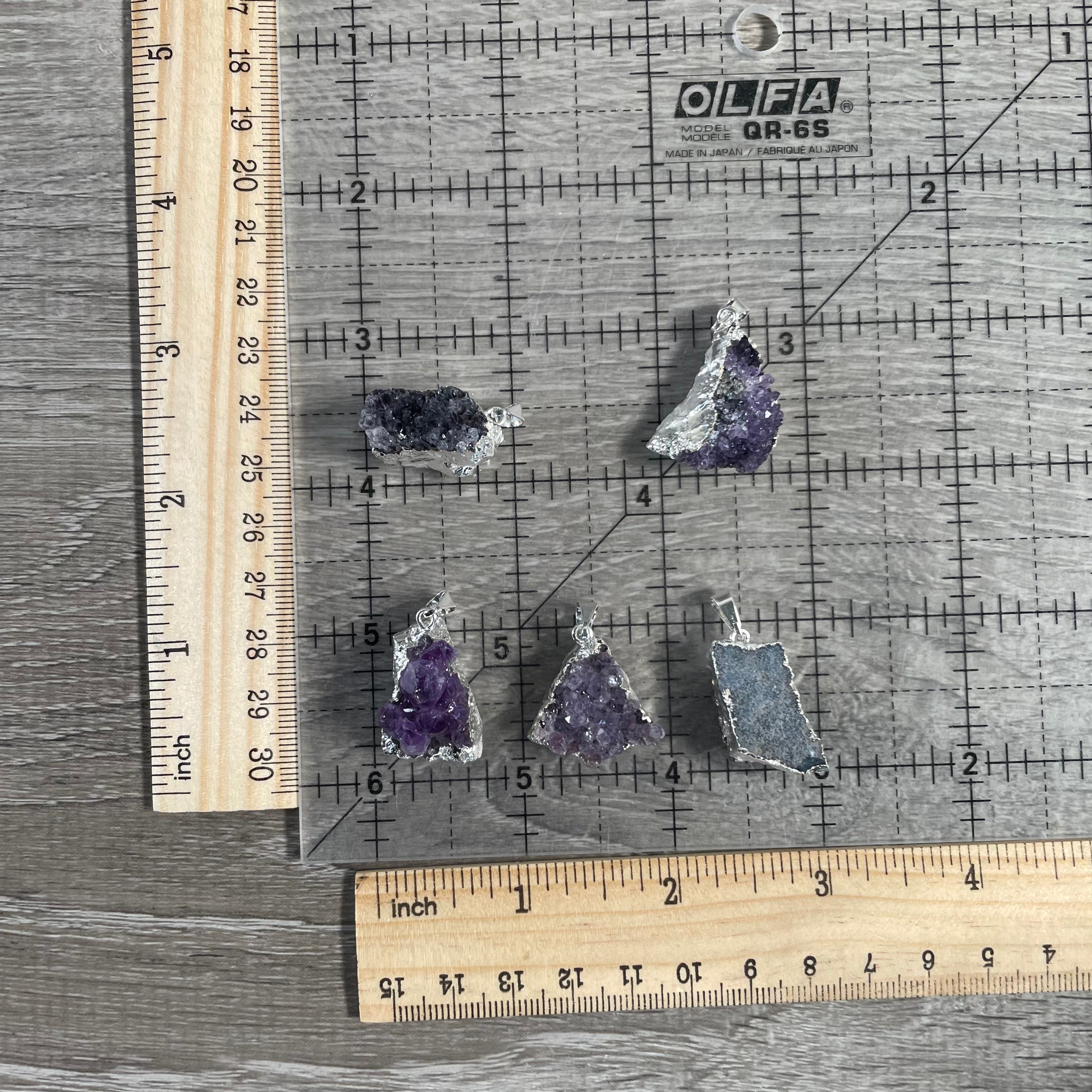Raw amethyst pendant featuring violet crystal formations and electroplated accents